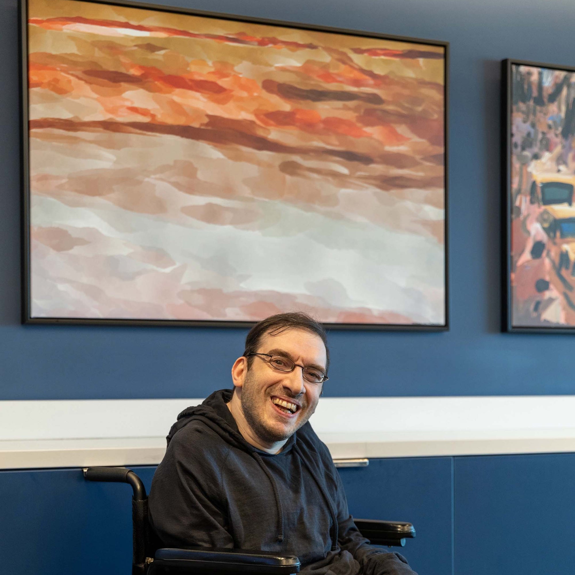 Person smiling in front of abstract art.