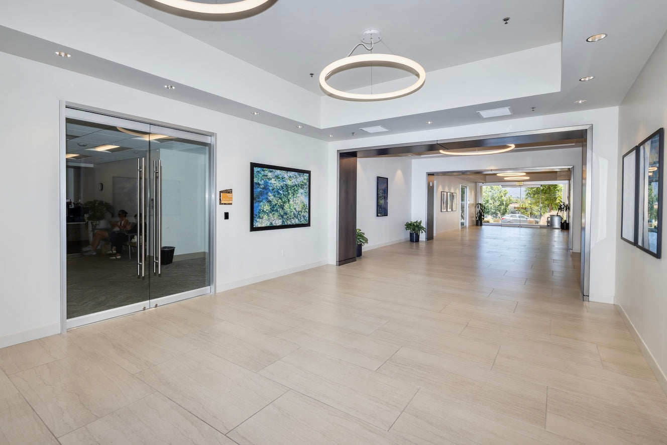A bright, open corridor at Westlake Landmark features a print reproduction of Outcrop at Hidden Beach by ArtLifting artist Michael Van Huffel, whose layered composition and organic textures reflect the natural beauty of the California landscape and harmonize with the building’s clean, light-filled design.