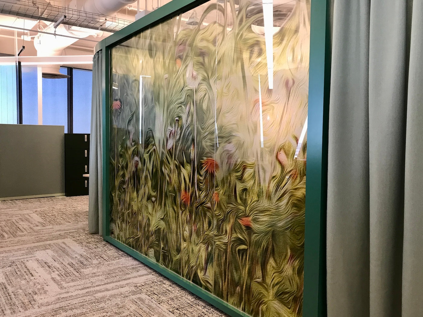 4. Side view of a teal-framed glass panel showcasing Pedernales Spring Yellow by Nancy Wood, a swirling abstract floral design in greens, yellows, and pink-oranges. The textured opacity maintains privacy while infusing the space with natural, organic color.