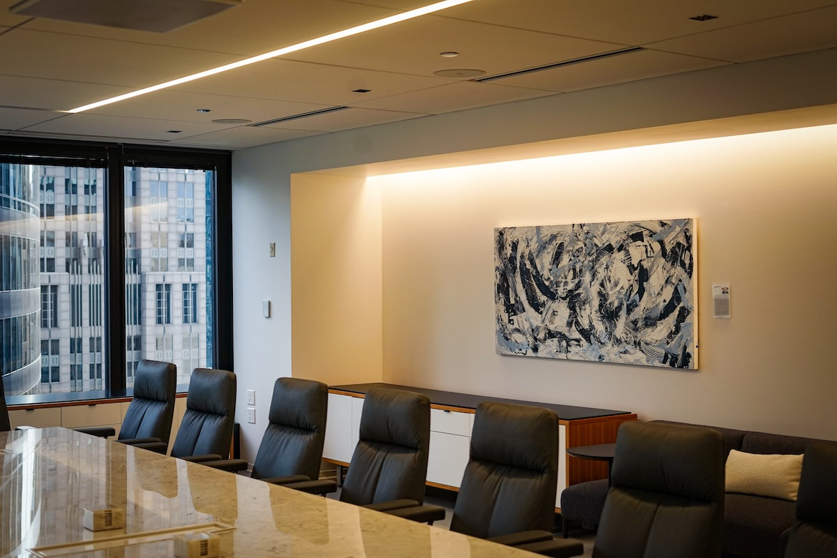 A-754 by Billy Megargel, original artwork measuring 72 inches wide, hangs in a spacious conference room. The sweeping grey and white brushstrokes of the piece echo the room’s calm, neutral palette of whites and greys, blending seamlessly with the contemporary furnishings. 