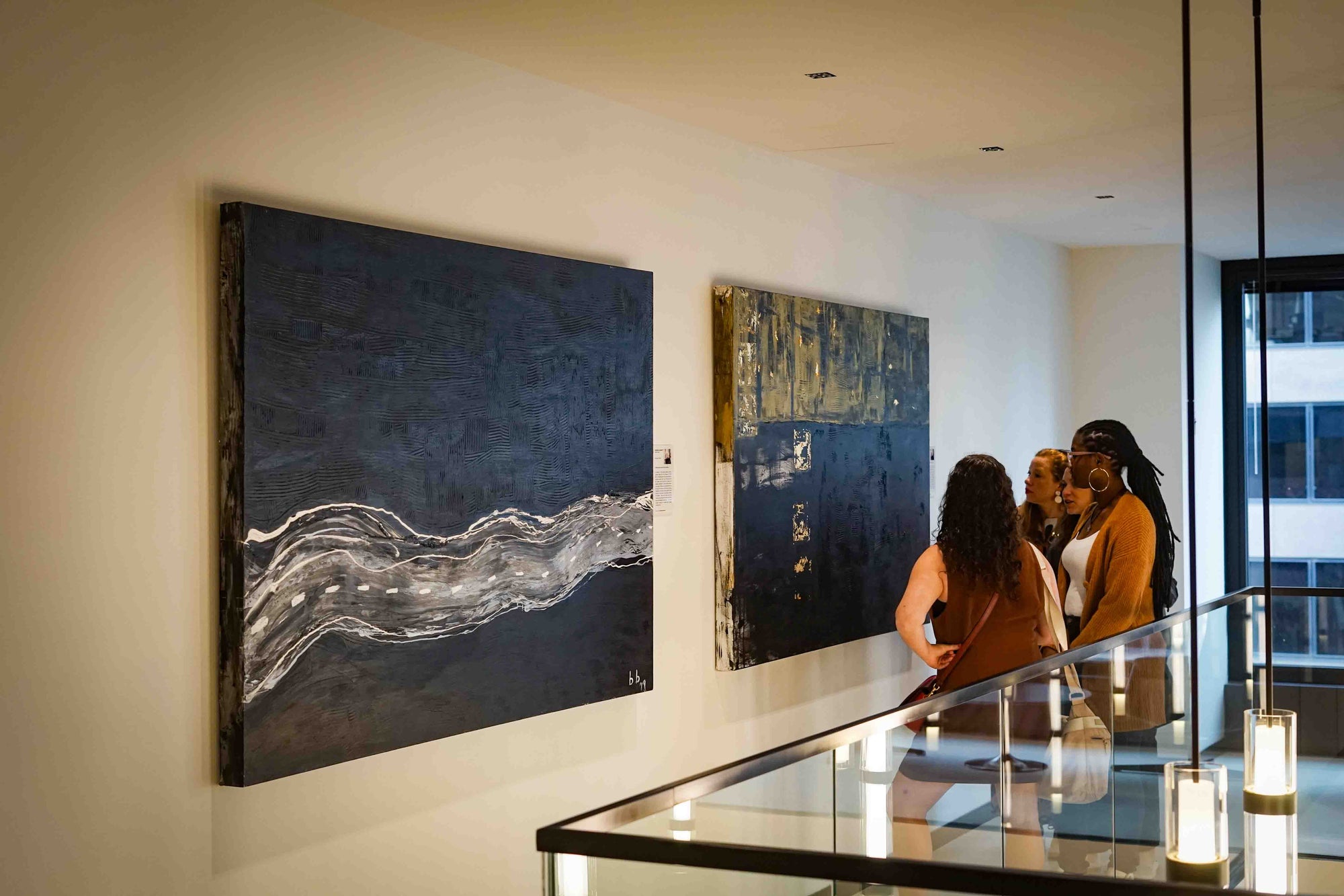 People looking at abstract art on a wall in an indoor setting.
