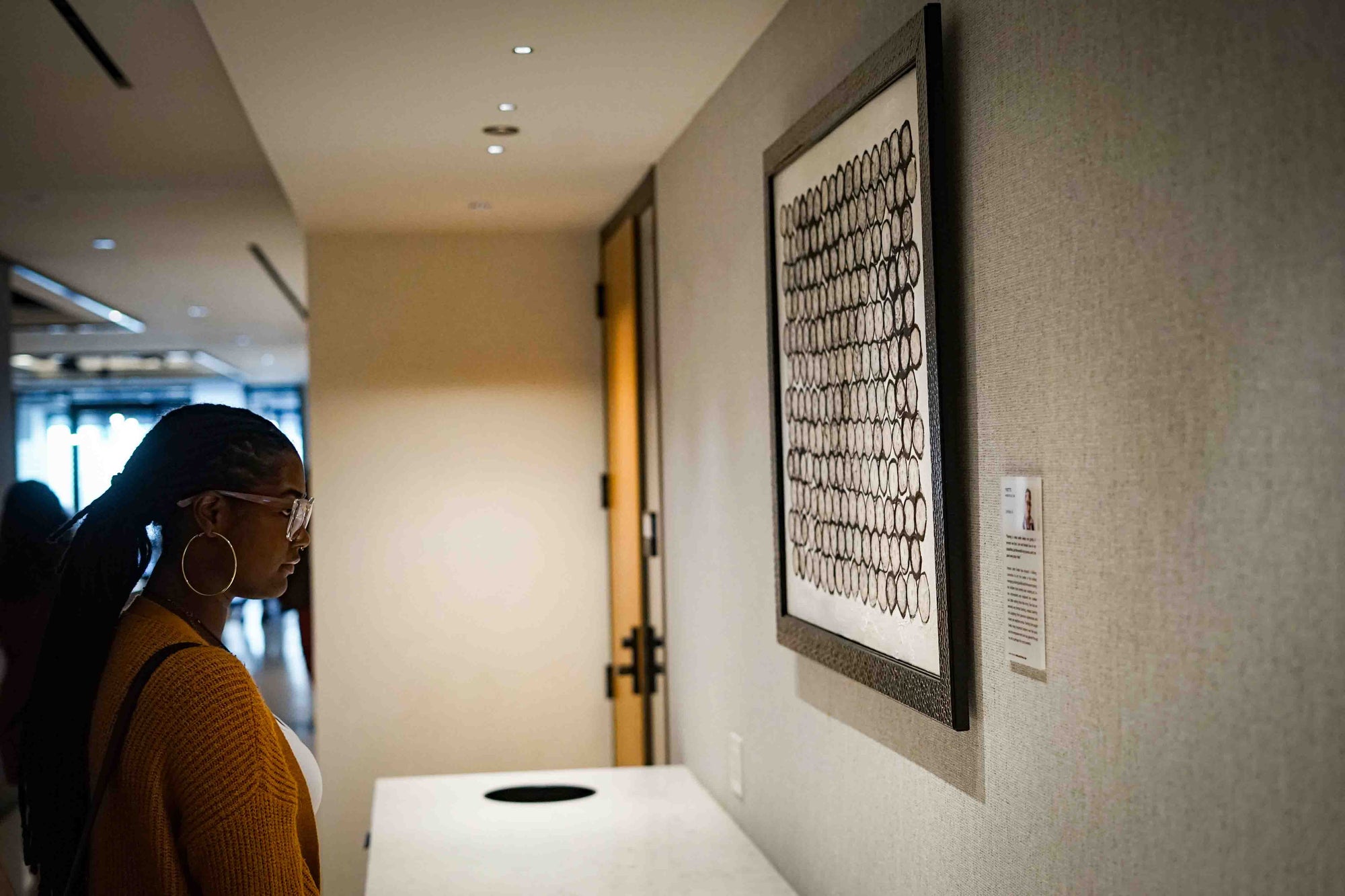 Woman looking at a piece of art on a wall in an indoor setting