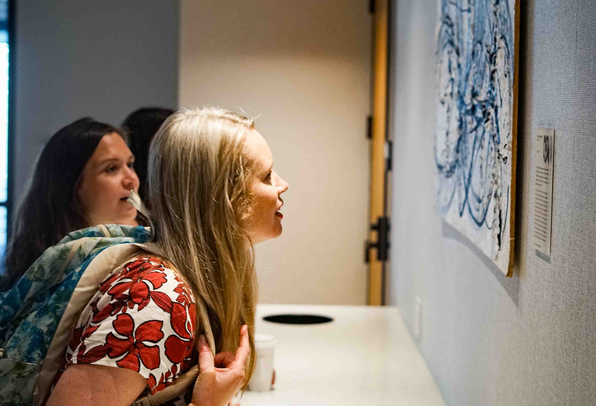 Two women looking at art on a wall.