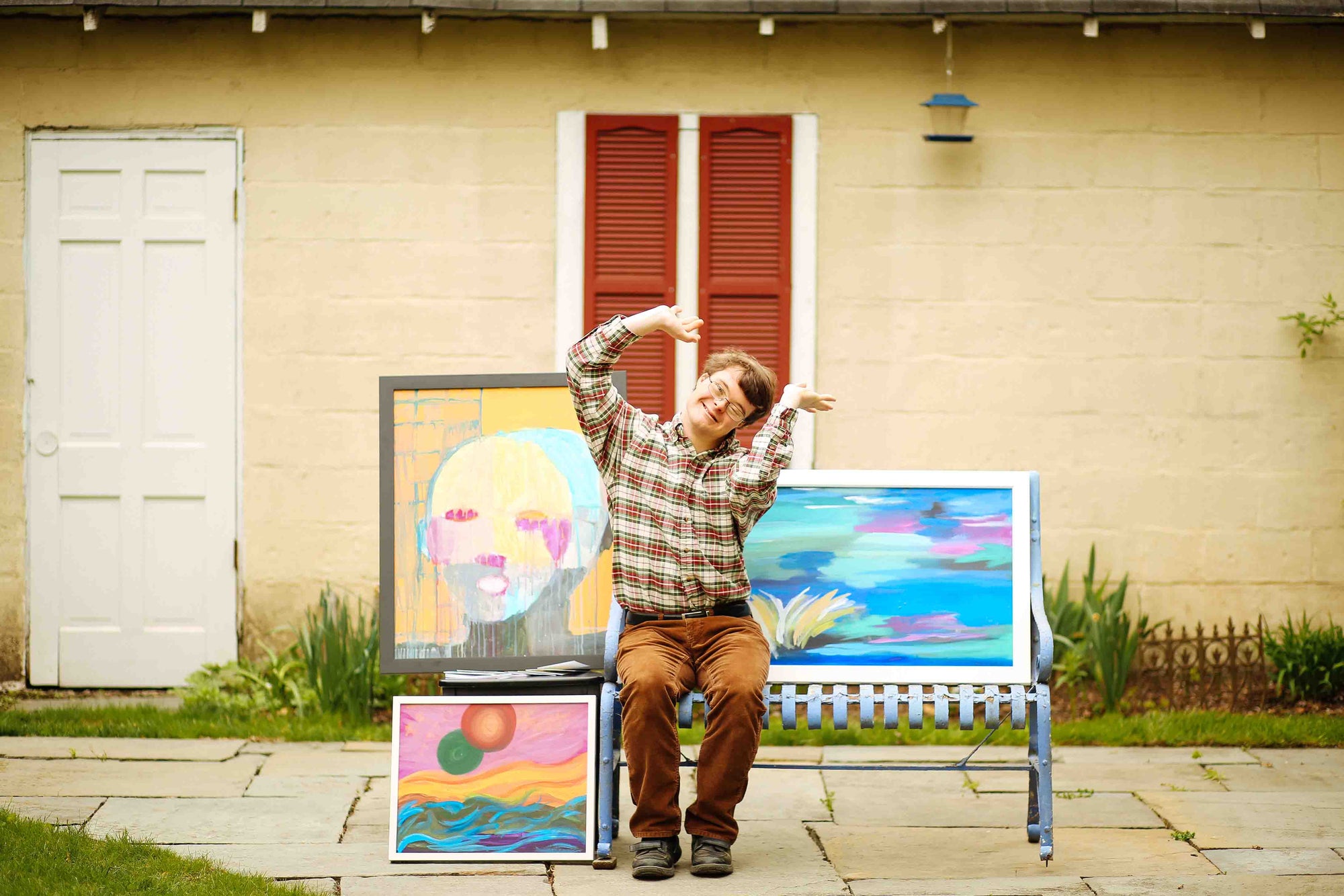 Person sitting on a bench with artwork in front of a house