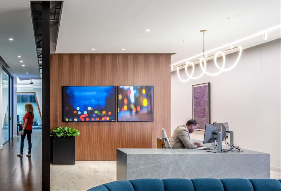 The headquarters reception area with a wood-paneled wall behind the desk. Two framed prints of artworks by Damiano Austin hang side by side, introducing vibrant, abstract compositions into the welcoming space.