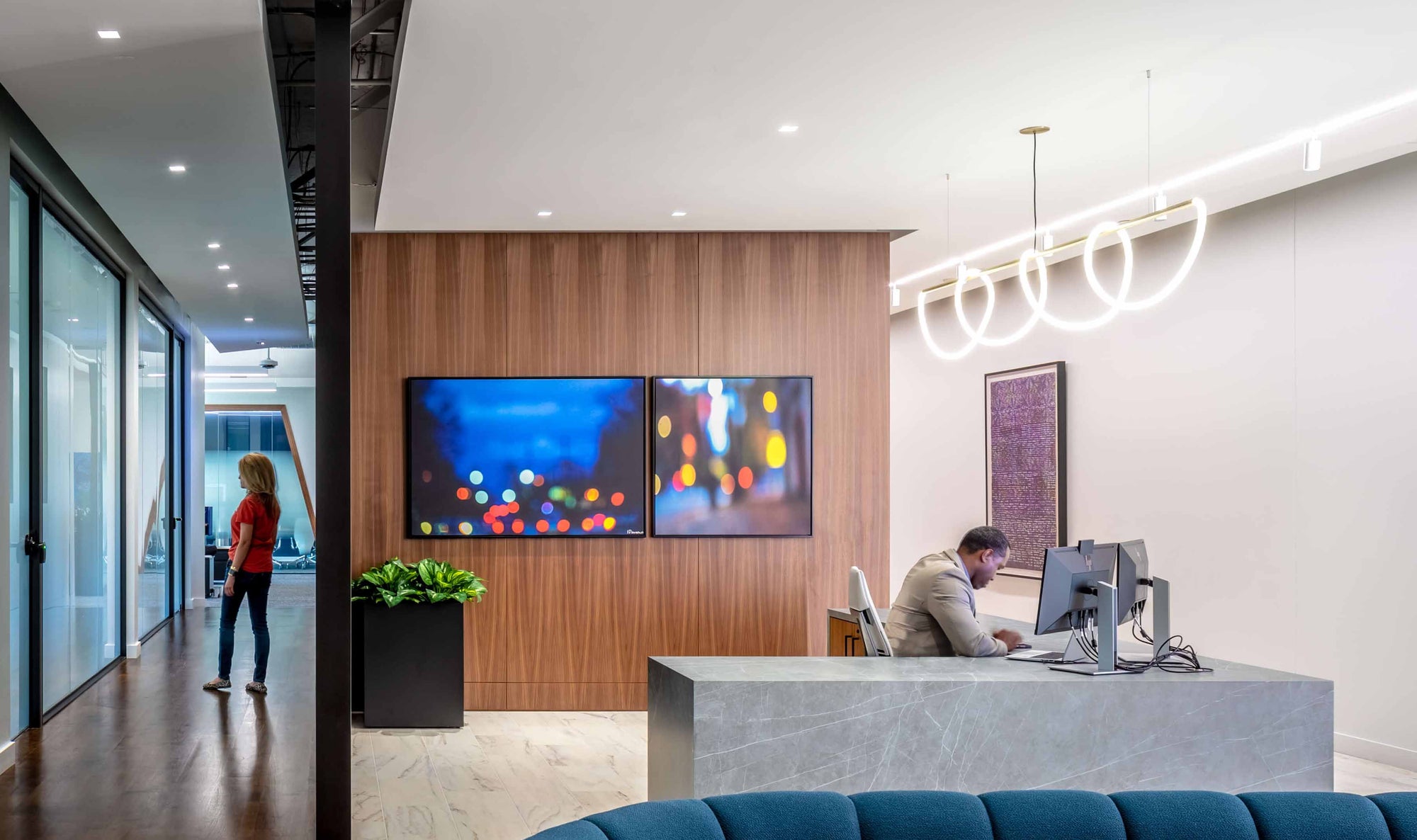 Modern office interior with reception desk and people working featuring workplace art.