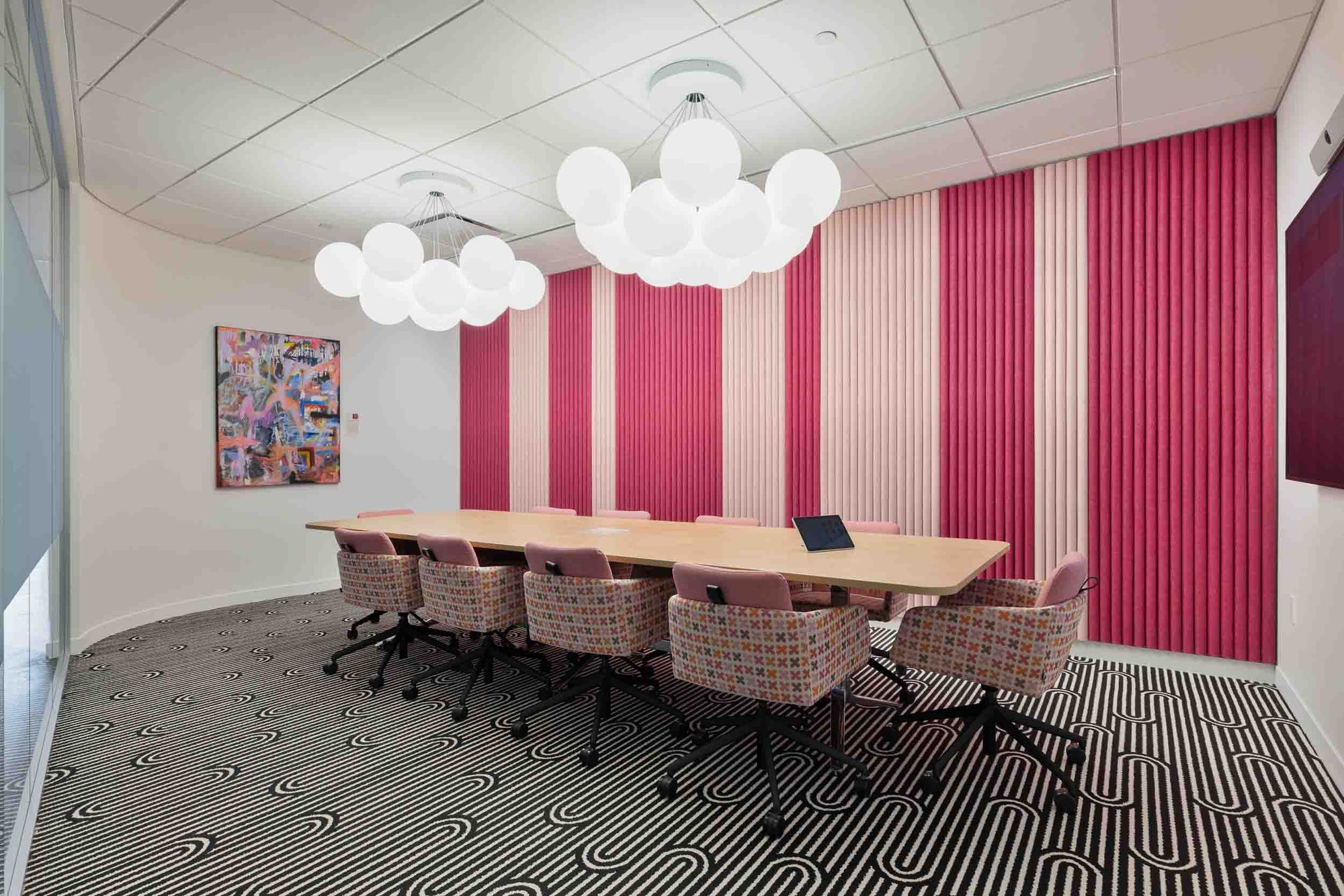 Modern conference room with a long table and chairs against a striped wall with original artwork.