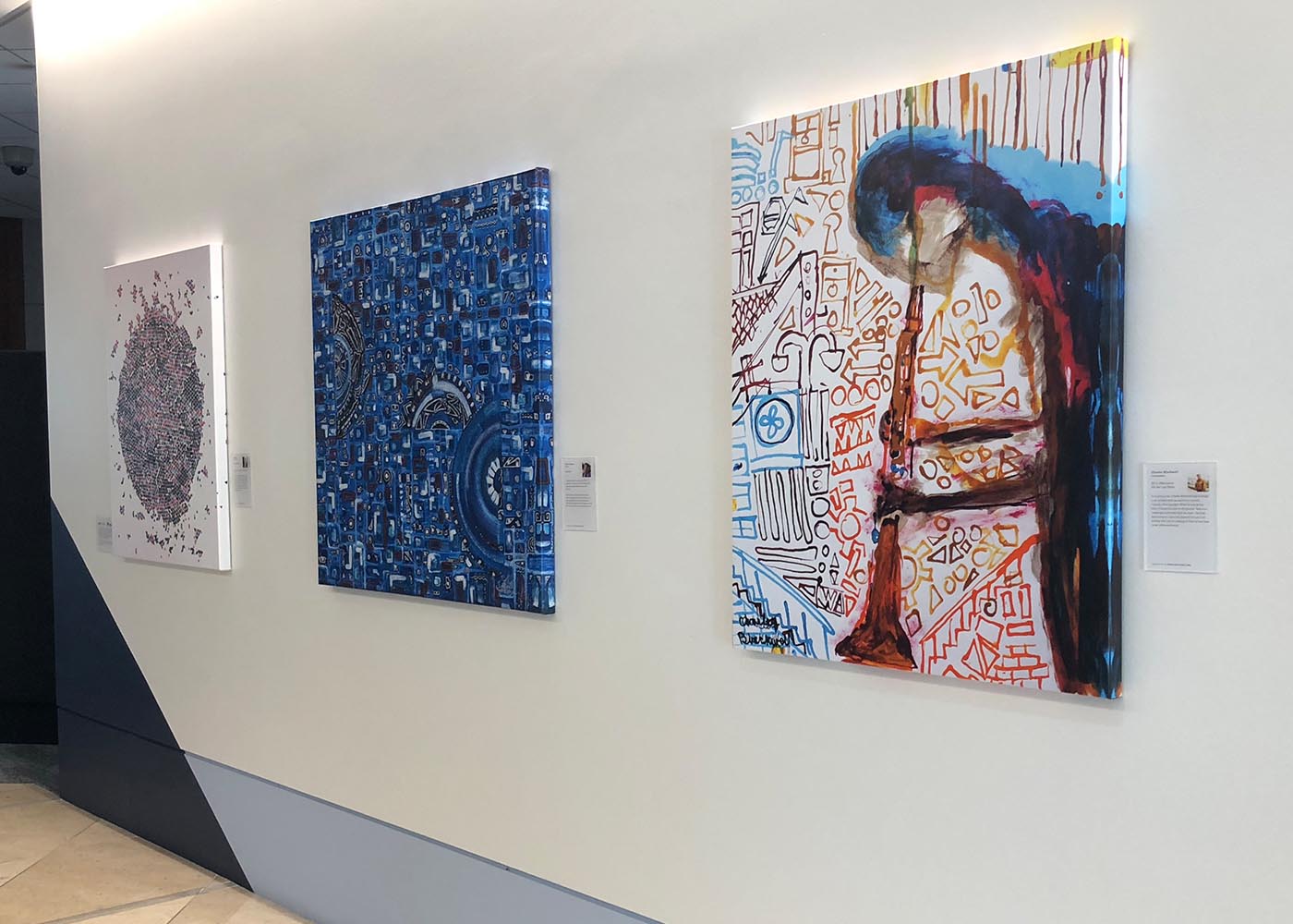 Artistic wall display with abstract artworks on a white wall.